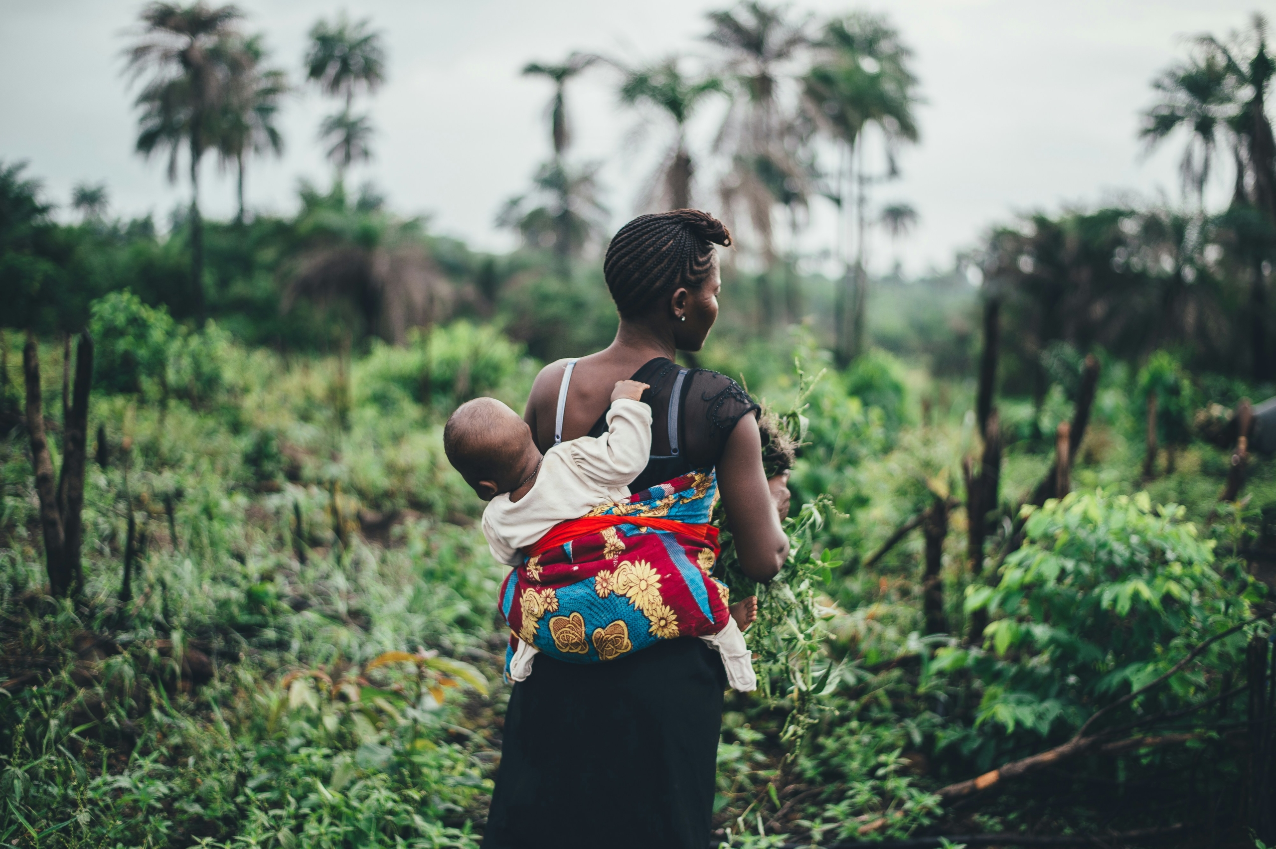 woman walking through a farm with her baby on her back