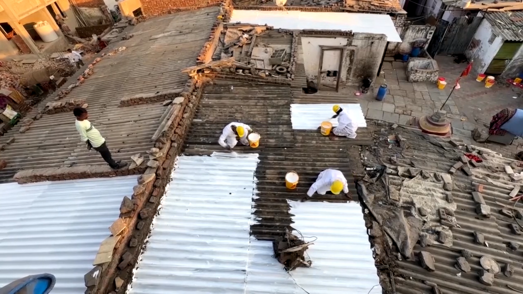 Roofs in an Indian slum being painted with a special white UV reflective paint