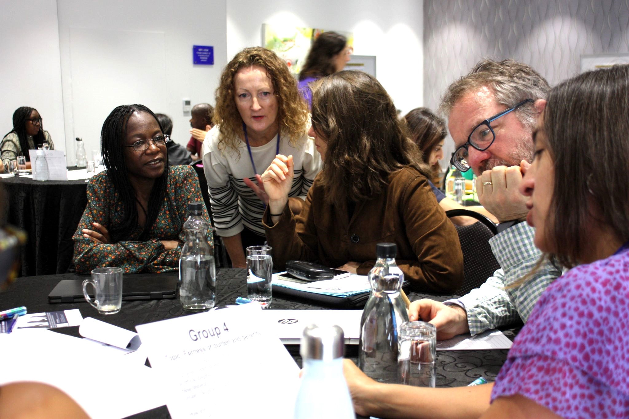 a group of people sitting at a table reading materials