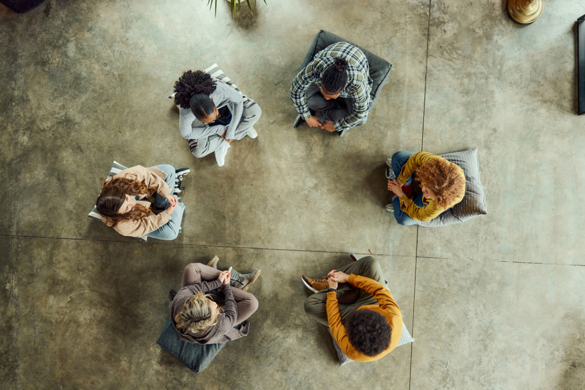 High angle view of team of creative people talking while having a casual meeting on floor in the office.